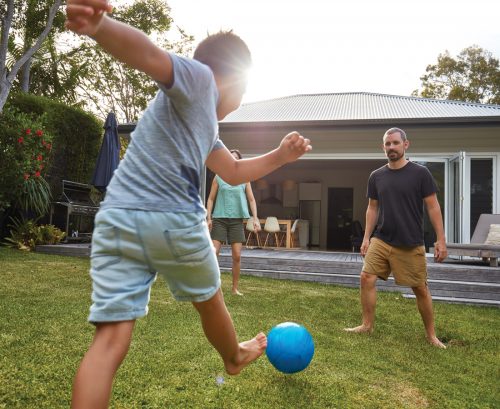 Boy kicking blue ball to father to represent men's health