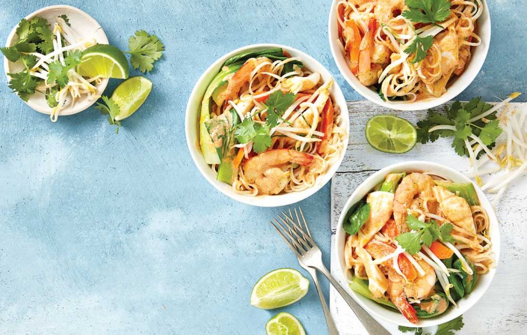 Three bowls of red Thai curry with prawns and noodles