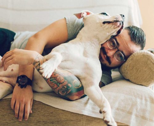 Man cuddling his dog on the sofa