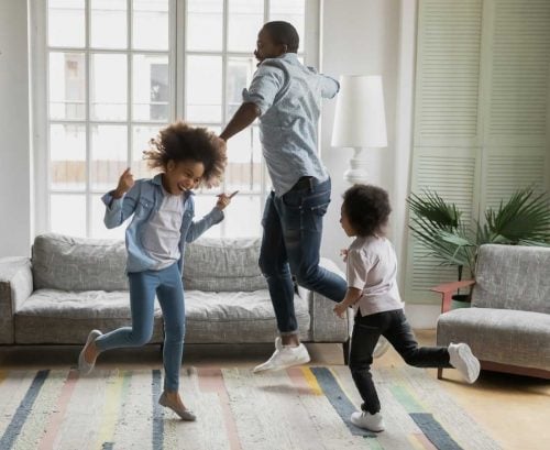 Father and daughters dancing energetically in living room