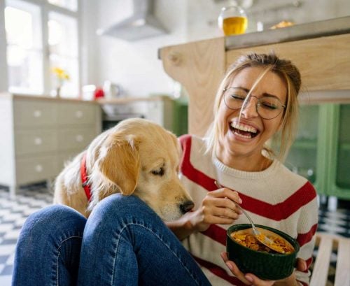 Happy woman eating cereal with dog
