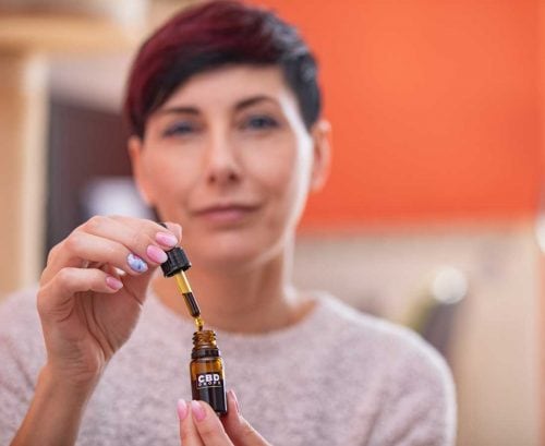 Woman holding dropper with CBD oil in it