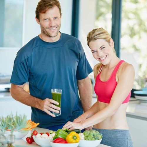 healthy looking couple making green smootihies
