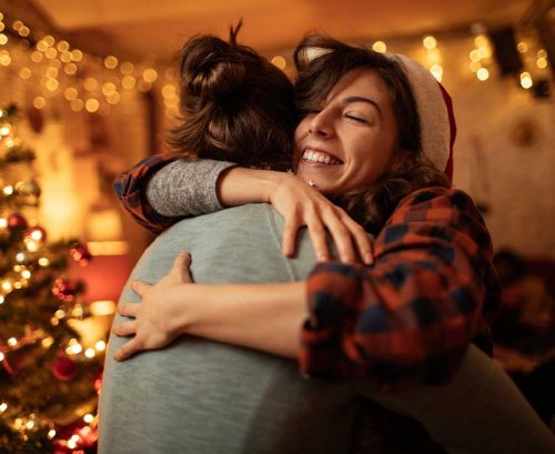 Two women hugging supportively by the Christmas tree