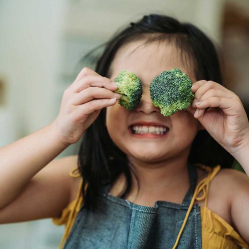 Young healthy girl with broccoli in her eyes