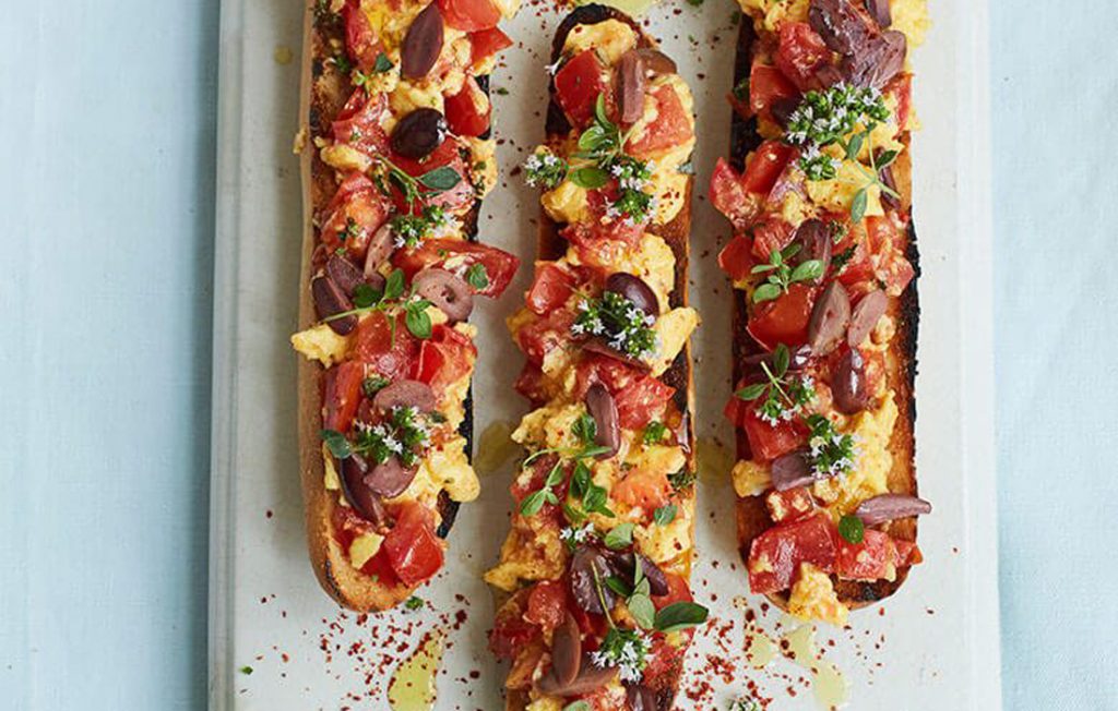 Tomato toasts with scrambled eggs, herbs and olives