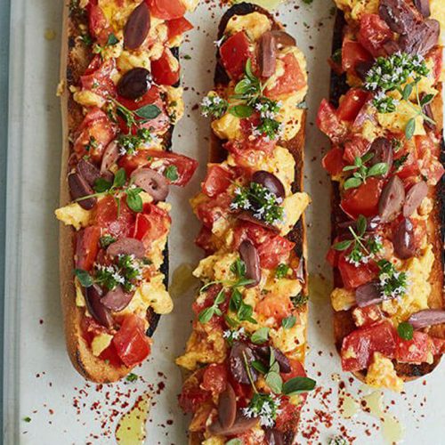 Tomato toasts with scrambled eggs, herbs and olives