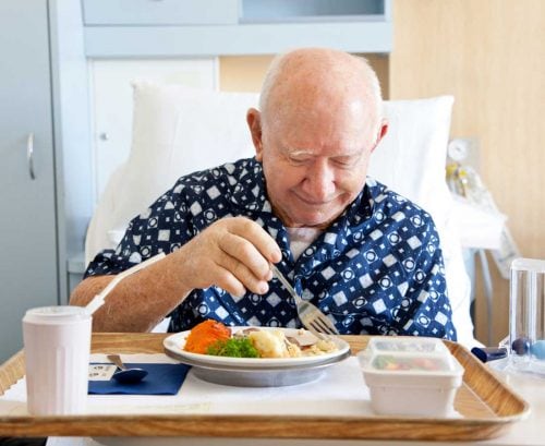 older man in hospital eating food
