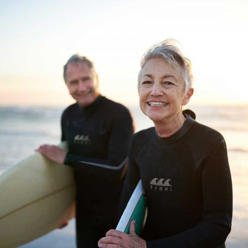 Healthy older couple with surfboards