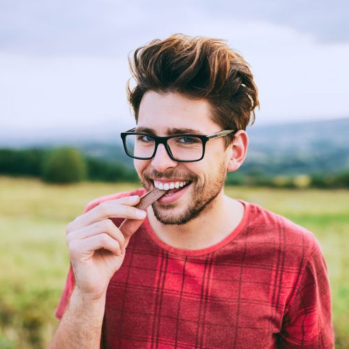 Young man eating chocolate in a field