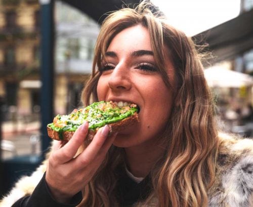 Young woman biting into avocado toast