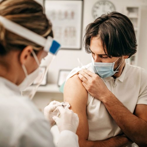 Man with mask on getting a COVID vaccination