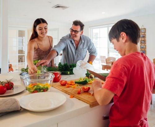 Ftaher and daughter and son preparing a healthy meal, looking happy