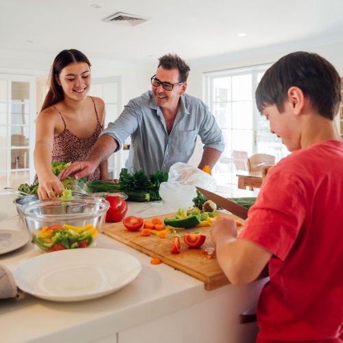 Ftaher and daughter and son preparing a healthy meal, looking happy