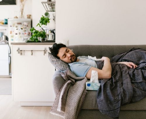Man lying on couch feeling sick