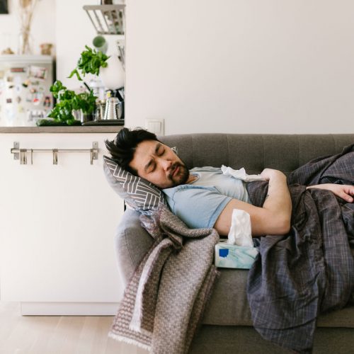 Man lying on couch feeling sick