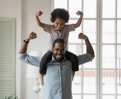 Man holding son on shoulders. Both are flexing their muscles
