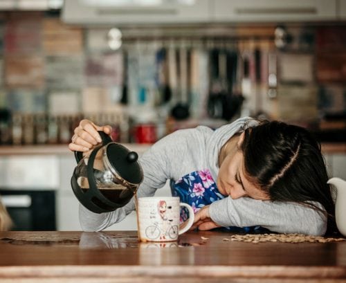 Tired woman puring coffee into an overflowing cup