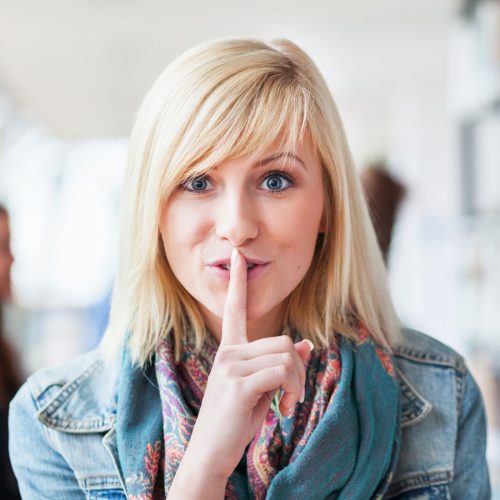 Woman going shhh against her finger like she's sharing a secret