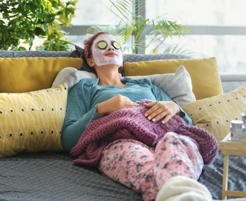 Woman lying on sofa with face mask on