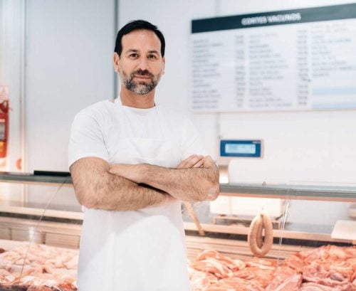 butcher standing in front of meat cabinet