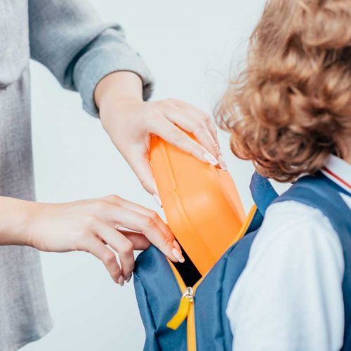 Mother putting lunchbox into child's bag