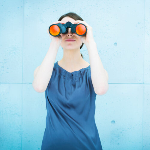 Woman looking out through binoculars