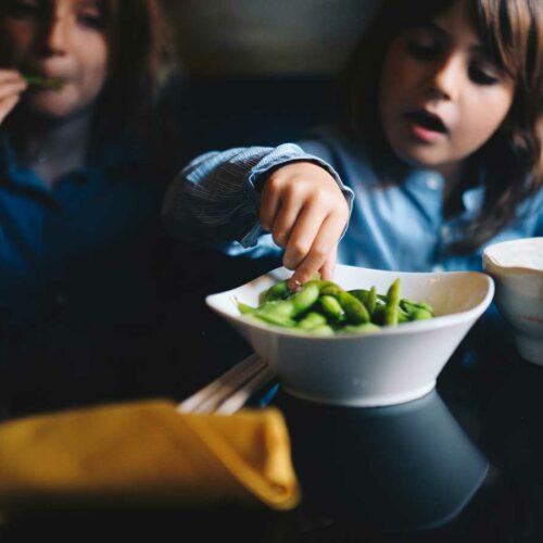 Kids eating from a bowl of edamame