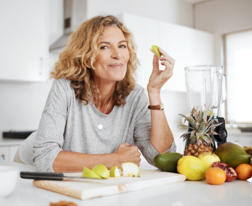 Woman at kitchen bench eating fruit