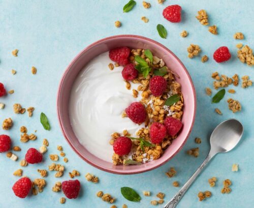 Bowl of yoghurt with raspberries and museli sprinkle over