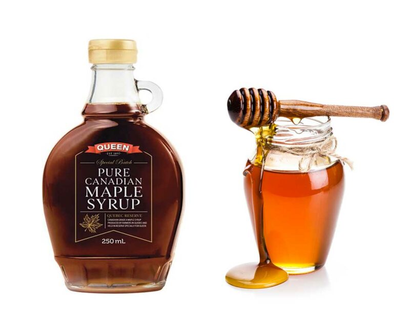 Bottle of maple syrup and a jar of honey with a honey spoon